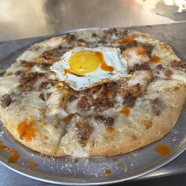 Breakfast pizza topped with an egg